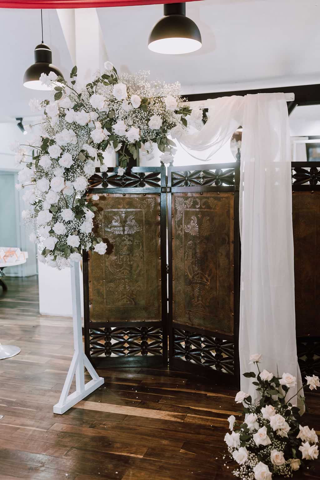 Arco de madera blanco con flores blancas combinadas y tela.